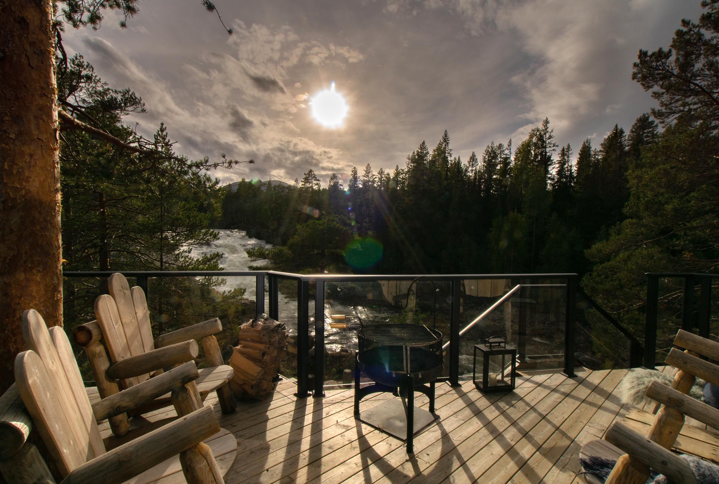 Treveranda med solide trelenestoler i motsol med utsikt mot en foss