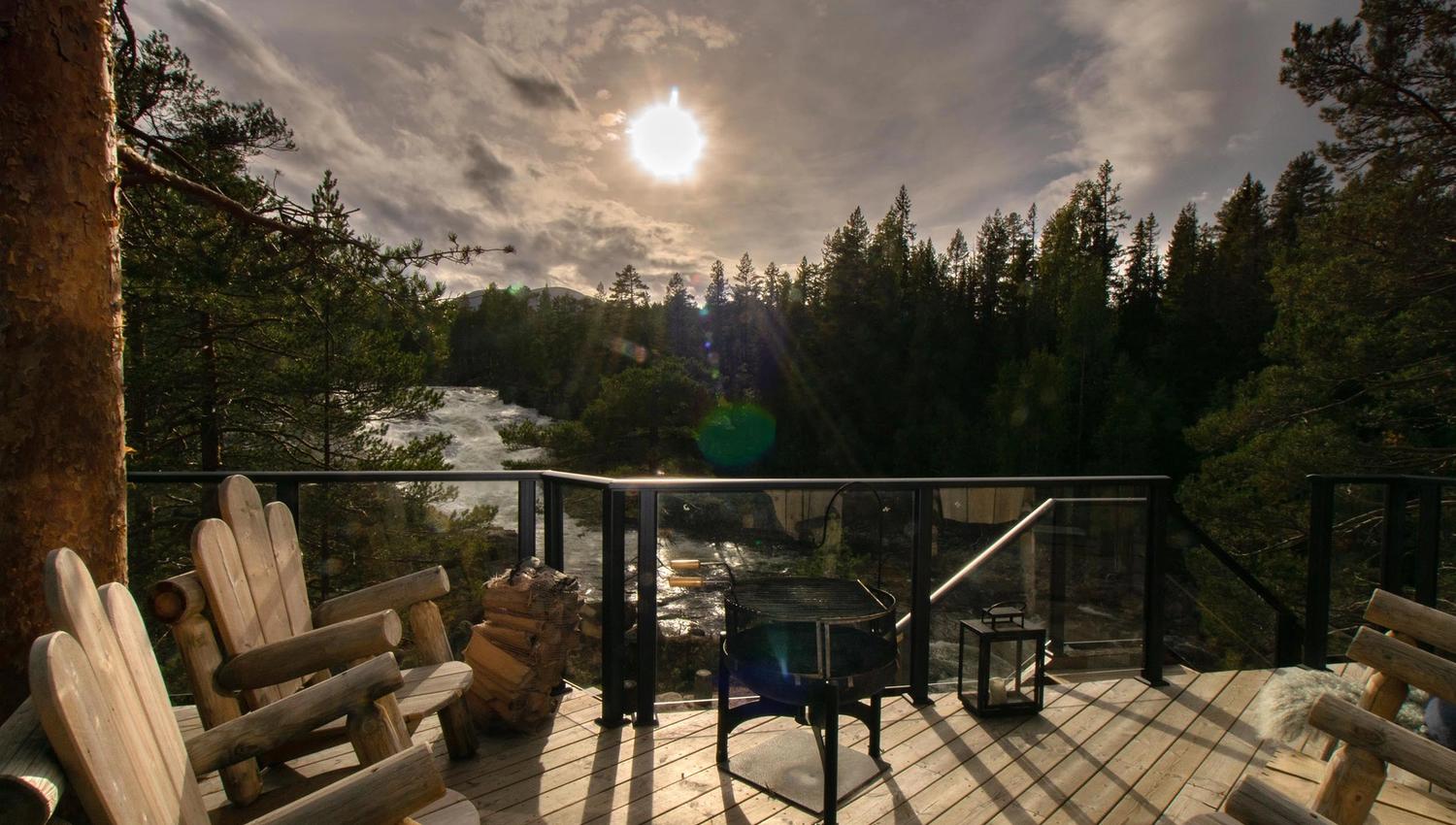 Treveranda med solide trelenestoler i motsol med utsikt mot en foss