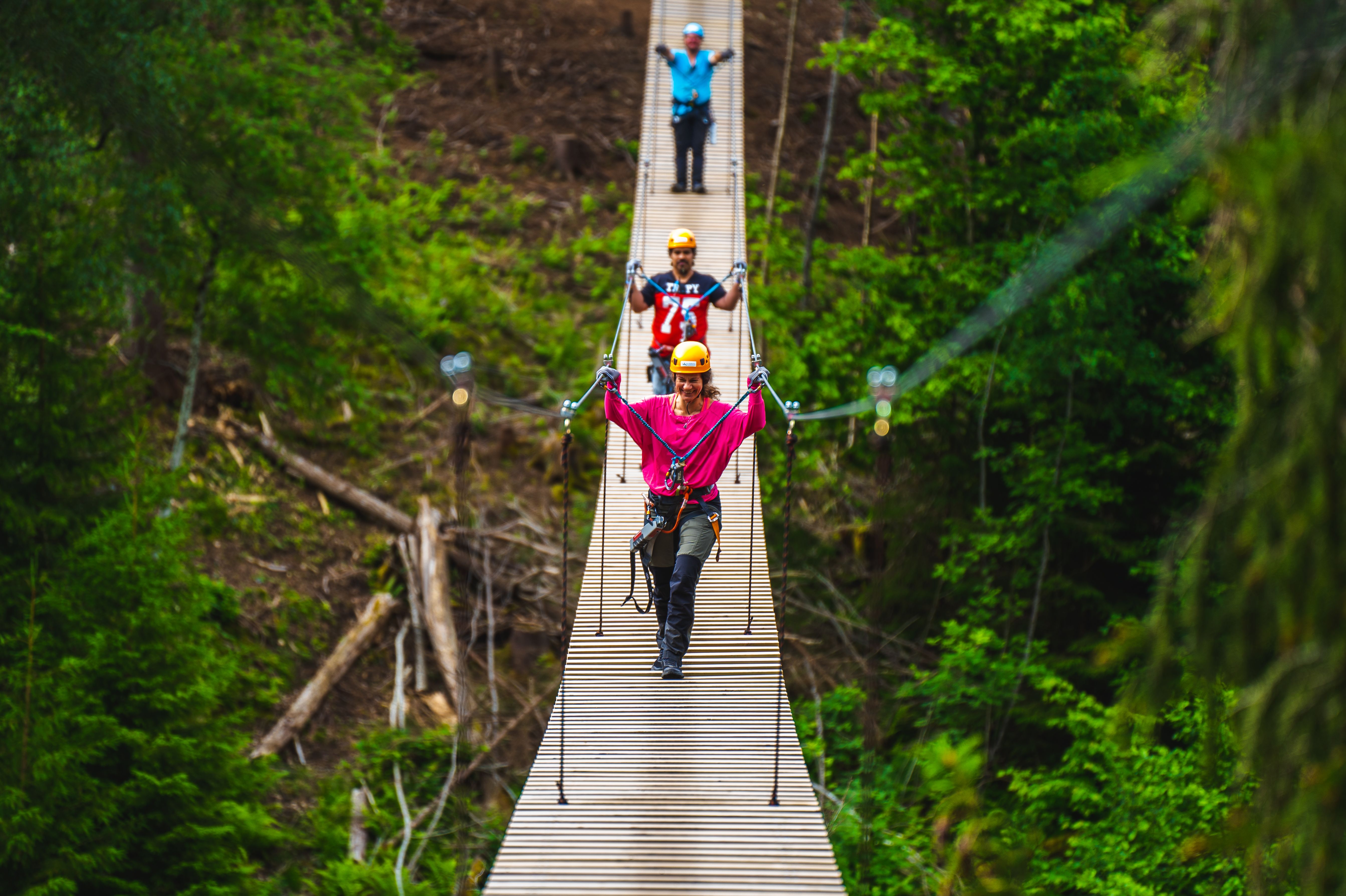 Tre personer som går over hengebroa i Via ferrata Haldenkanalen