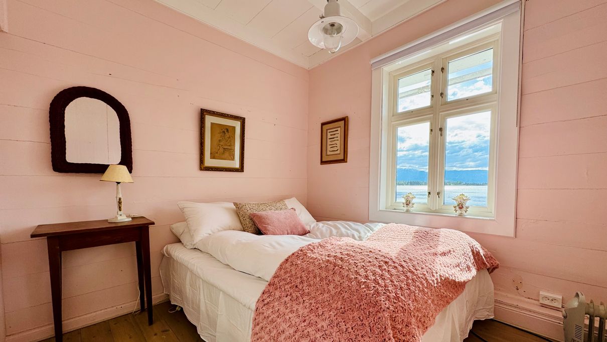 Det rosa rommet på Kramsjø Gjestgiveri, med mjuke pastelltonar og utsikt mot fjorden.