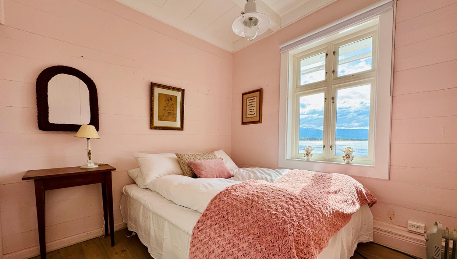 Det rosa rommet på Kramsjø Gjestgiveri, med mjuke pastelltonar og utsikt mot fjorden.