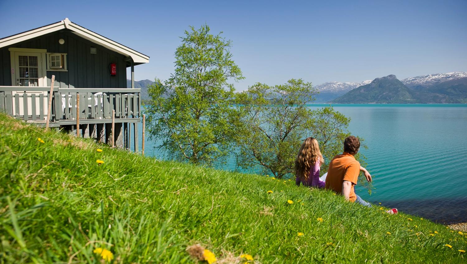 Par nyt utsikta frå Oddland Camping mot fjorden og snødekte fjell.