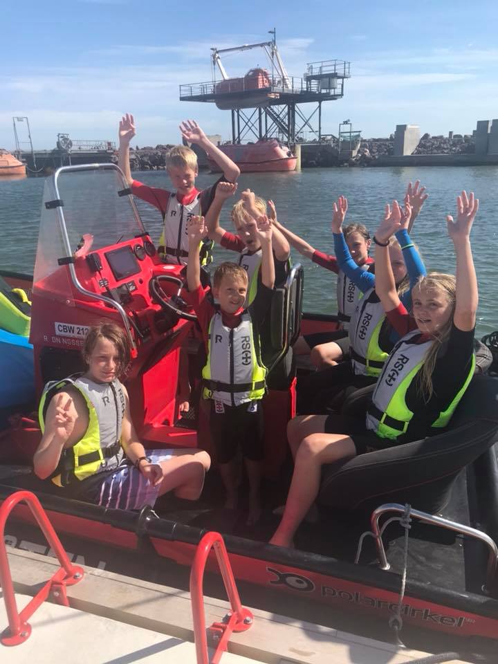 Barn med flytevest i båt ved brygge