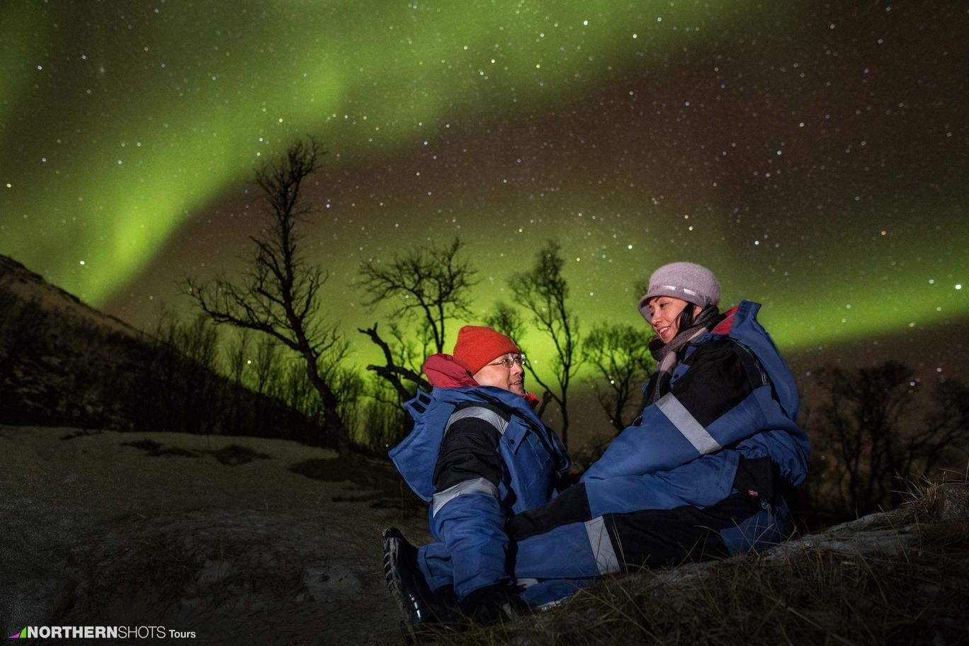 To gjester som sitter under nordlyset