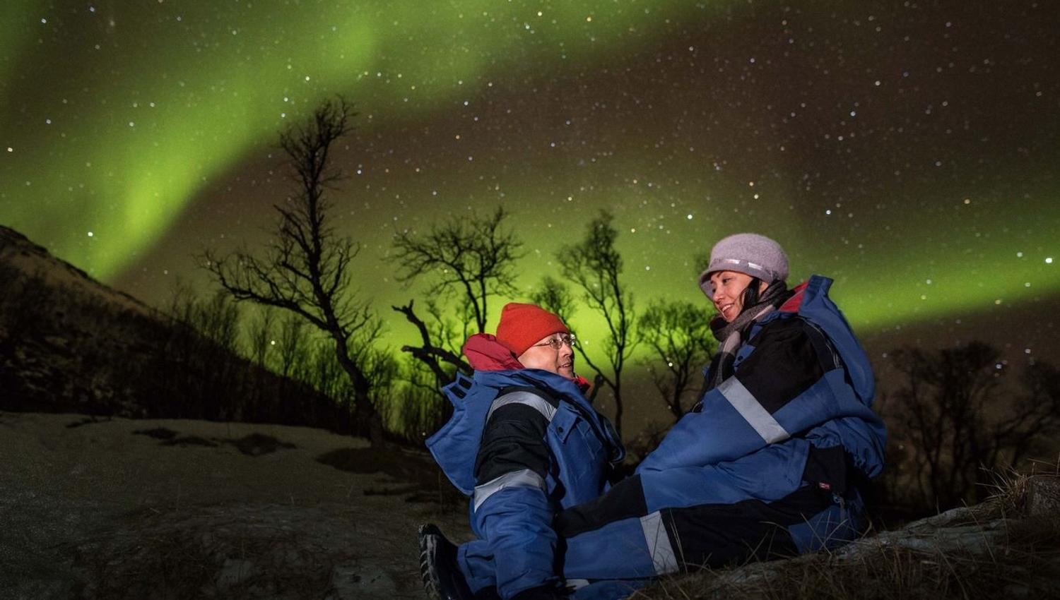 To gjester som sitter under nordlyset