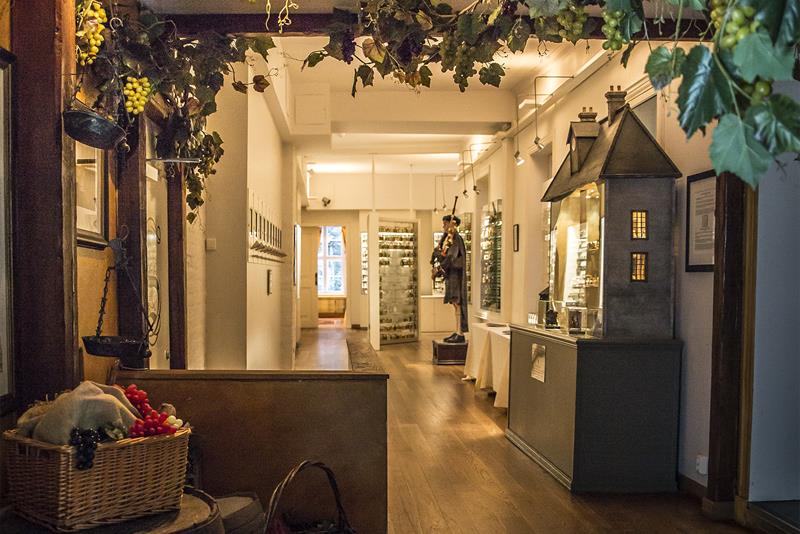 Utstilte småflasker i monter, voksdukke med sekkepipe