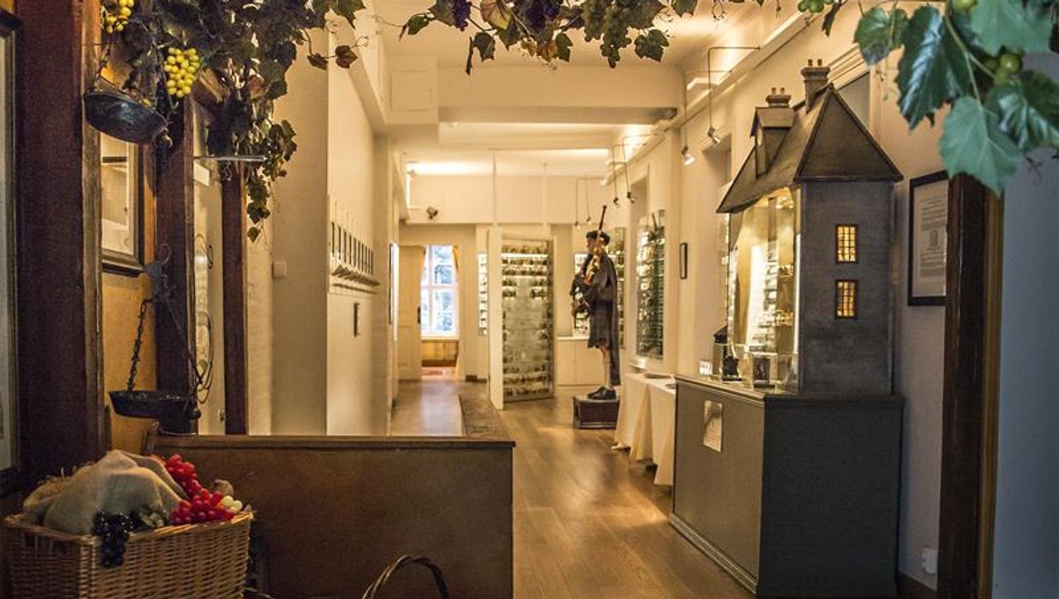 Utstilte småflasker i monter, voksdukke med sekkepipe