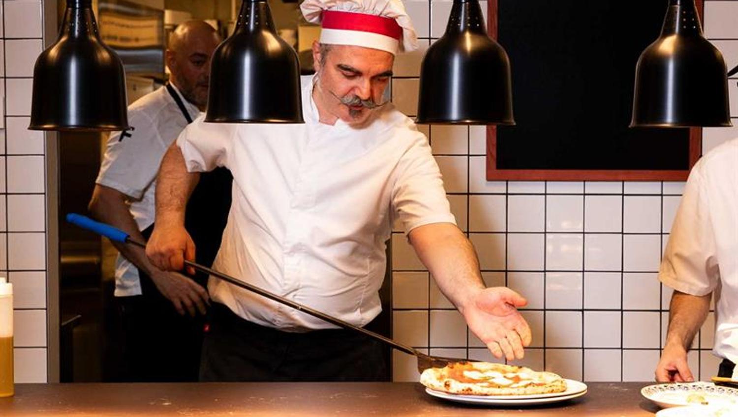 Kokk Francesco De Palma som tar en pizza ut av ovnen