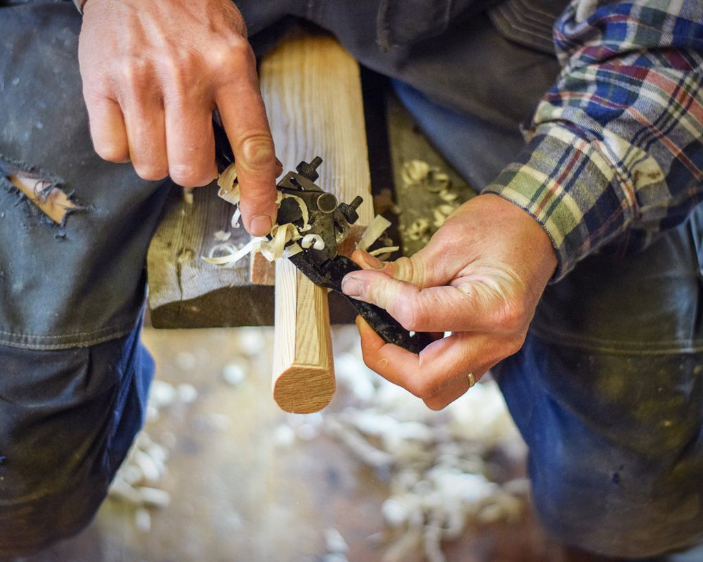 A craftsman shaping wood in the workshop at Hardanger Maritime Center.