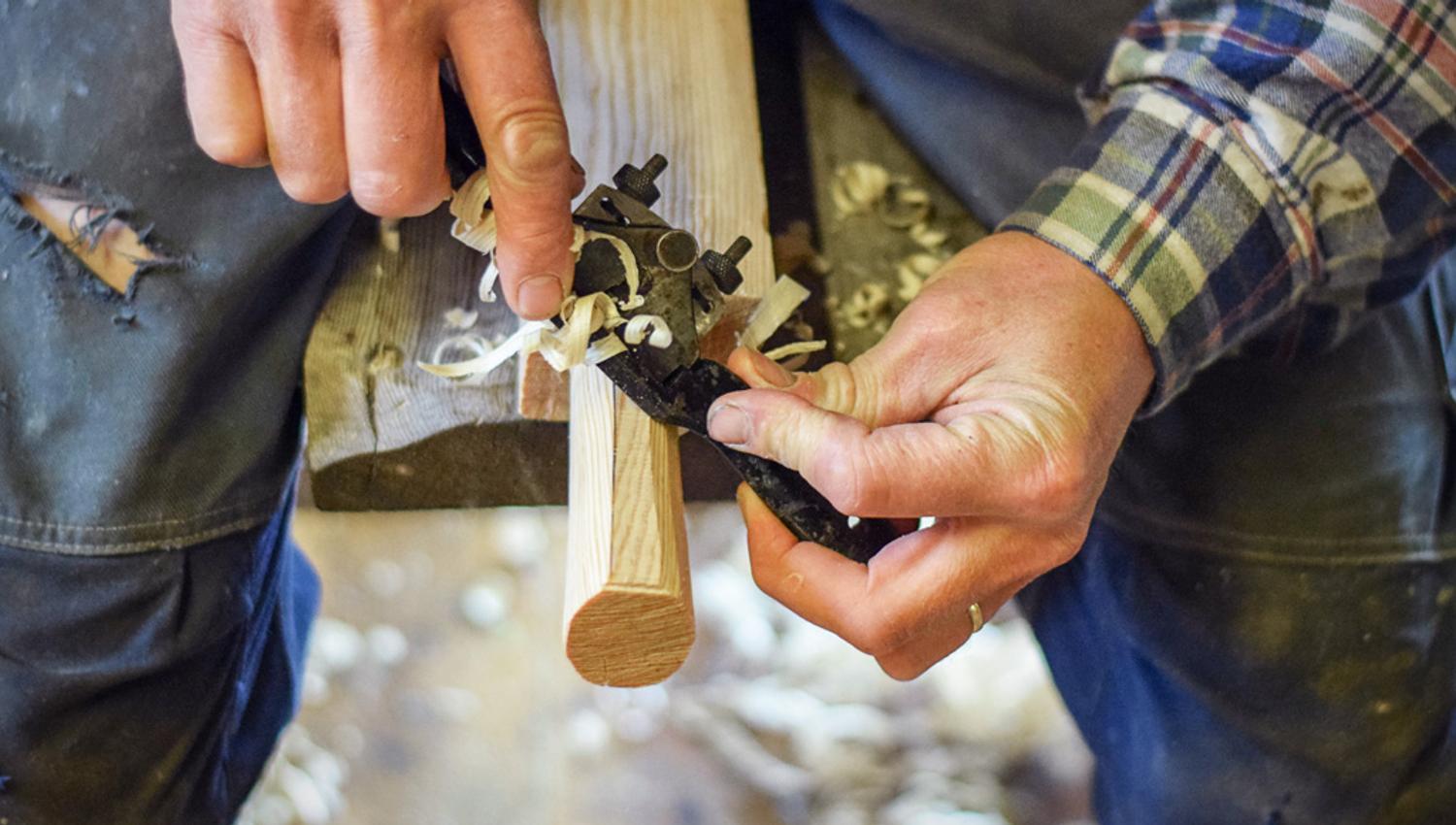 A craftsman shaping wood in the workshop at Hardanger Maritime Center.