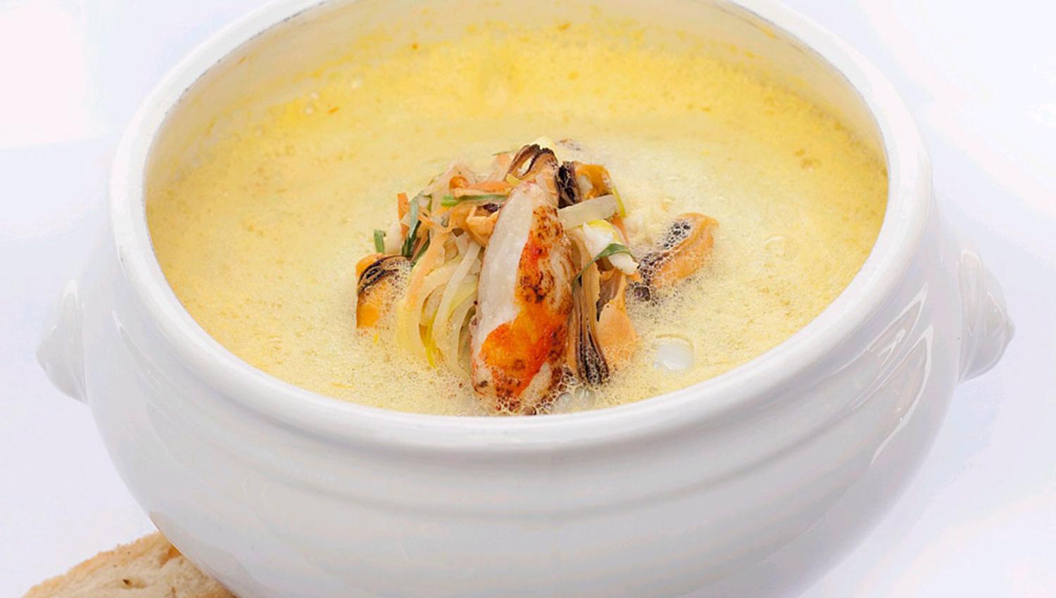 Detaljbilde av en suppe i en skål med brød ved siden av.