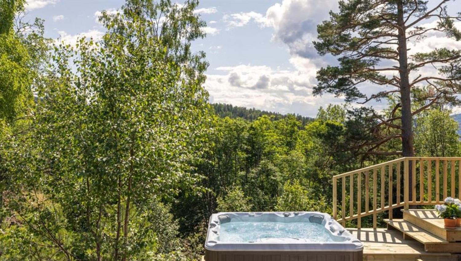 En badestamp på en terrasse omgitt av trær og utsikt over naturen.