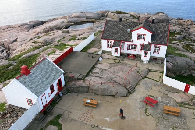 Overview image of the house at Ryvingen Lighthouse. The house is white with red details (red trim) and a black roof.