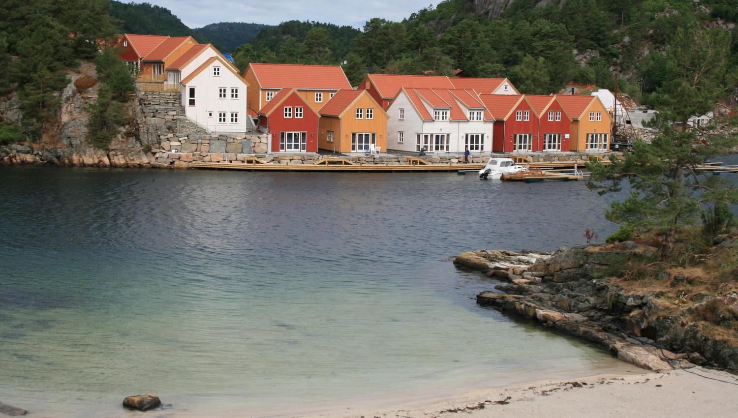 Moderne feriehus i forskjellige farger ved havet, I forgrunnen er en strand.