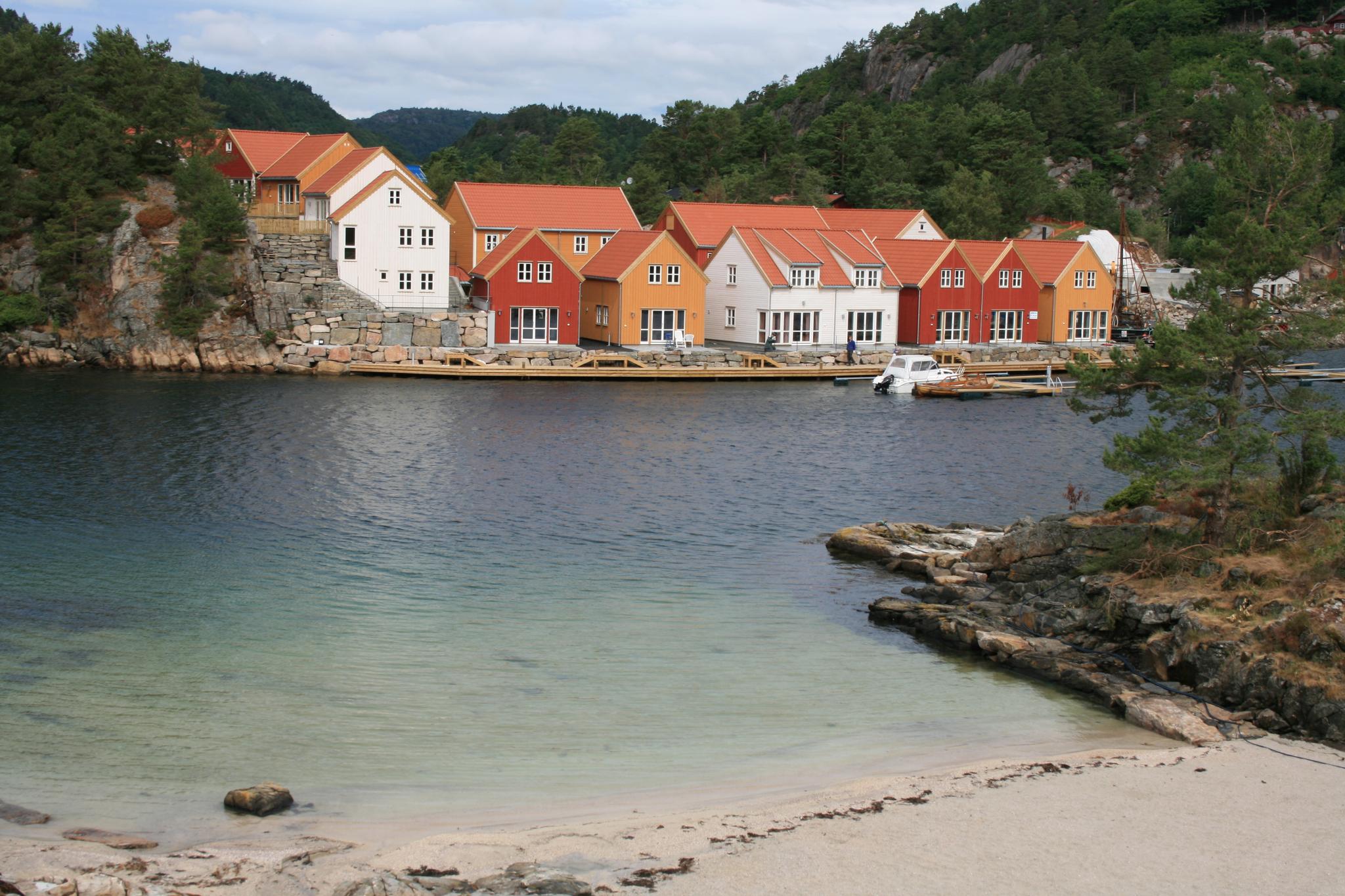 Moderne feriehus i forskjellige farger ved havet, I forgrunnen er en strand.