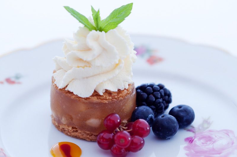 Detail photo of a dessert on a white plate with flowers on.