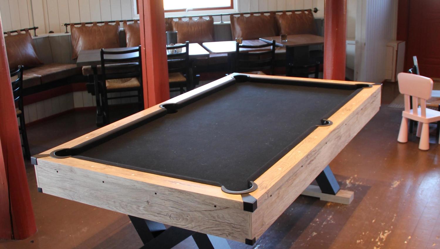 A pool table on a wooden floor.