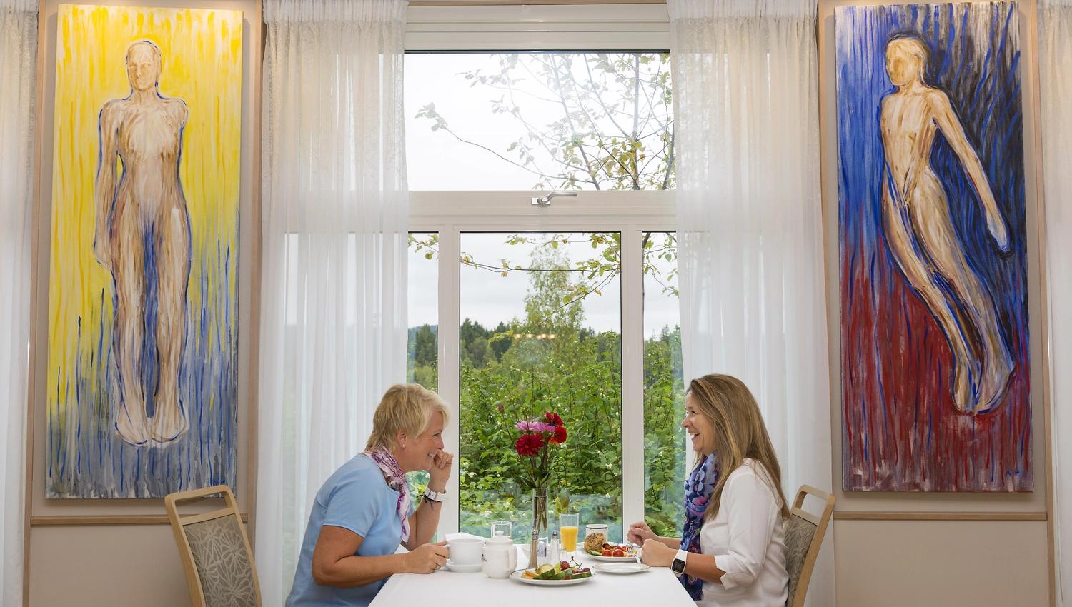 2 damer som spiser med malerier på veggen