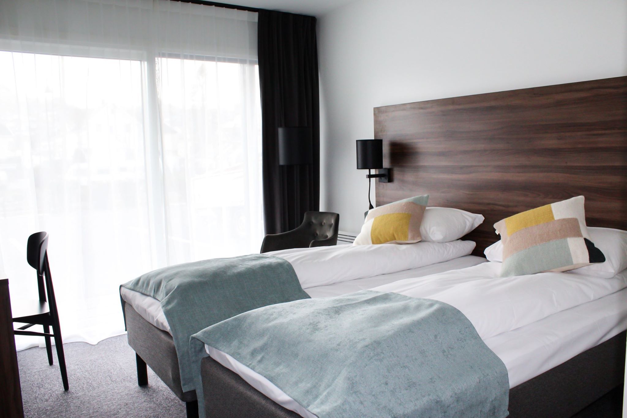 Lyst hotellrom med to enkeltsenger og utsikt mot fjorden frå balkongen.