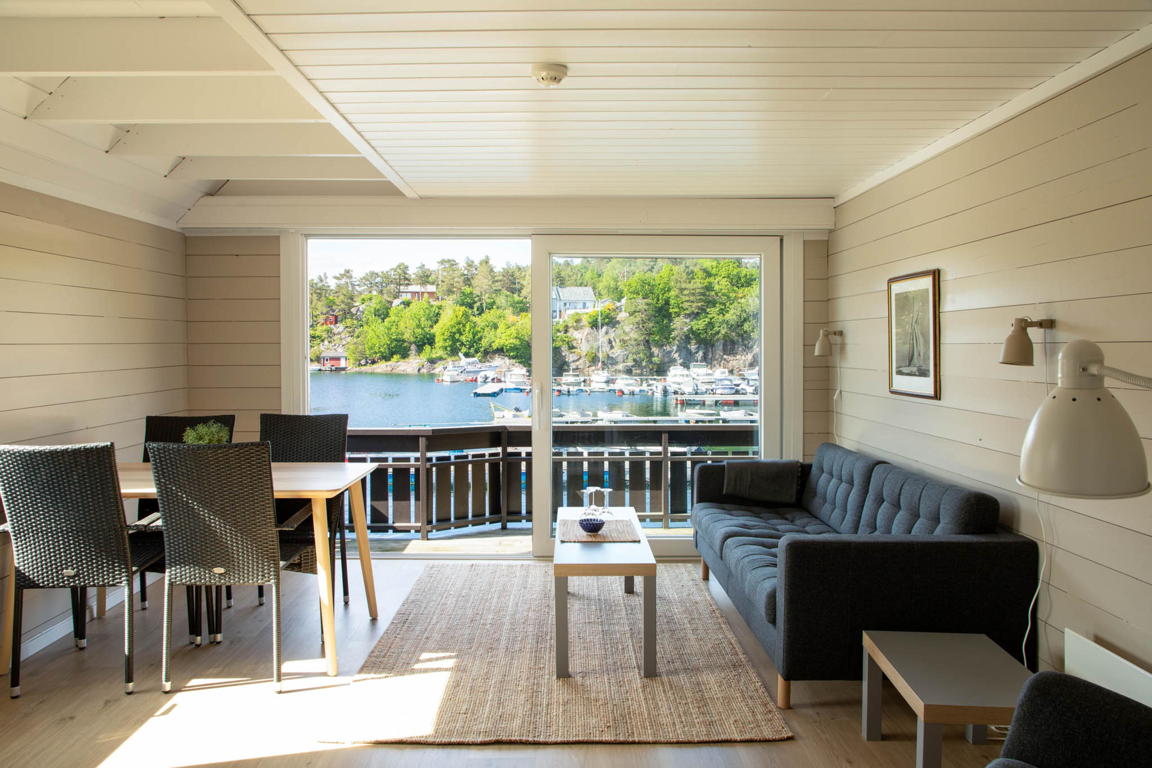 stue med sofa og spisebord og utsikt til sjøen