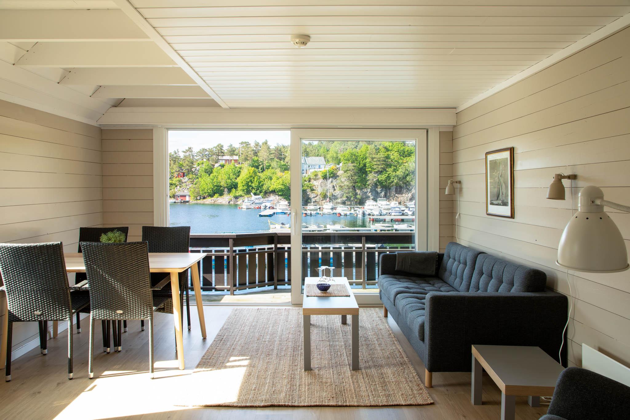 stue med sofa og spisebord og utsikt til sjøen