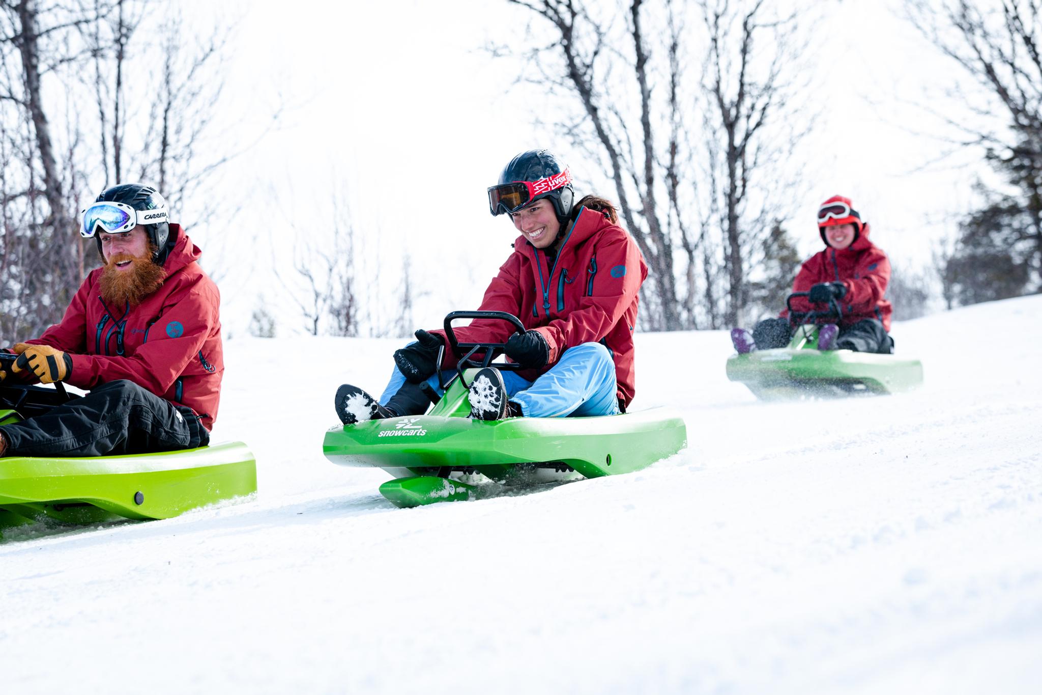 A group of three boys is sliding down the hill on sleds.
