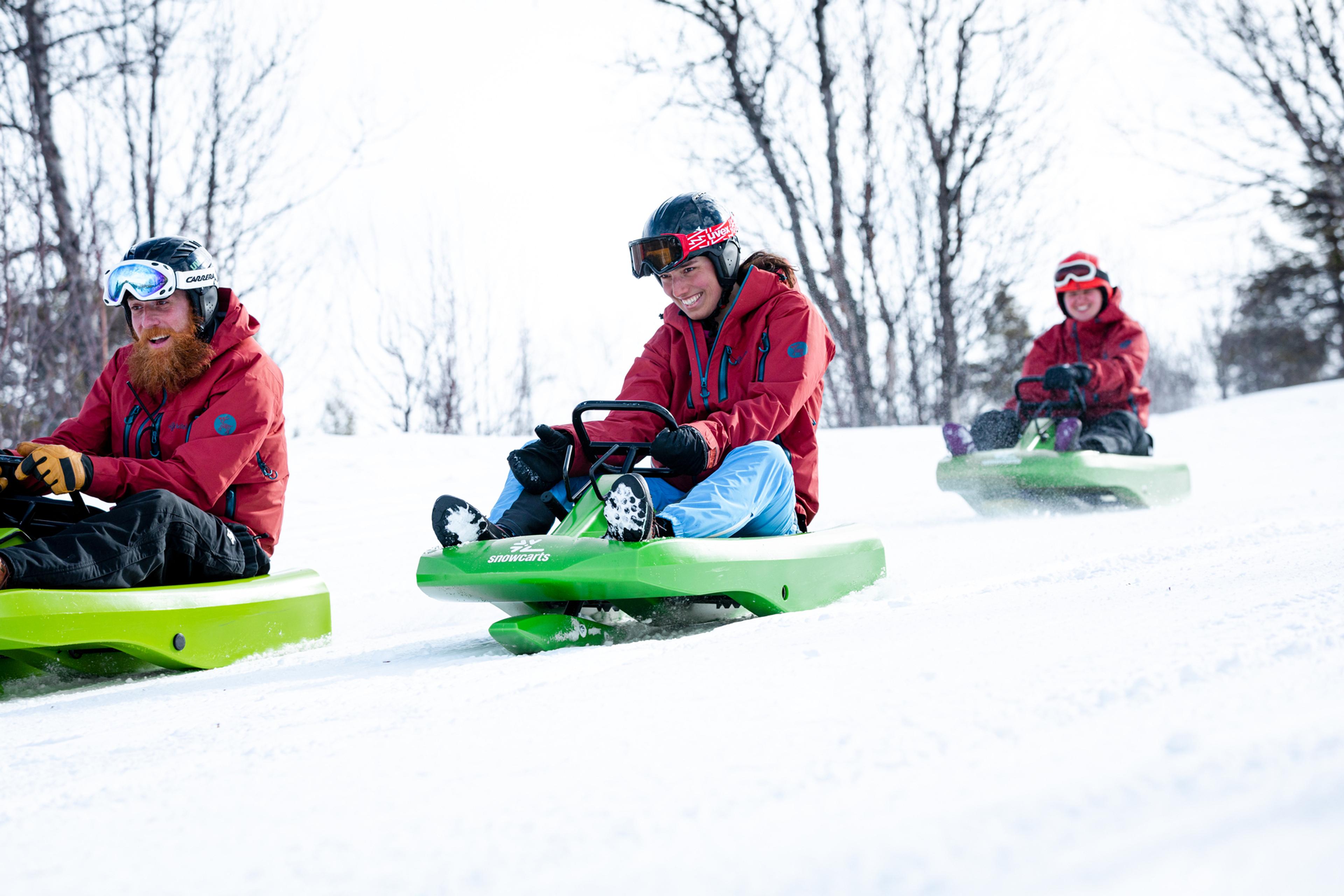A group of three boys is sliding down the hill on sleds.