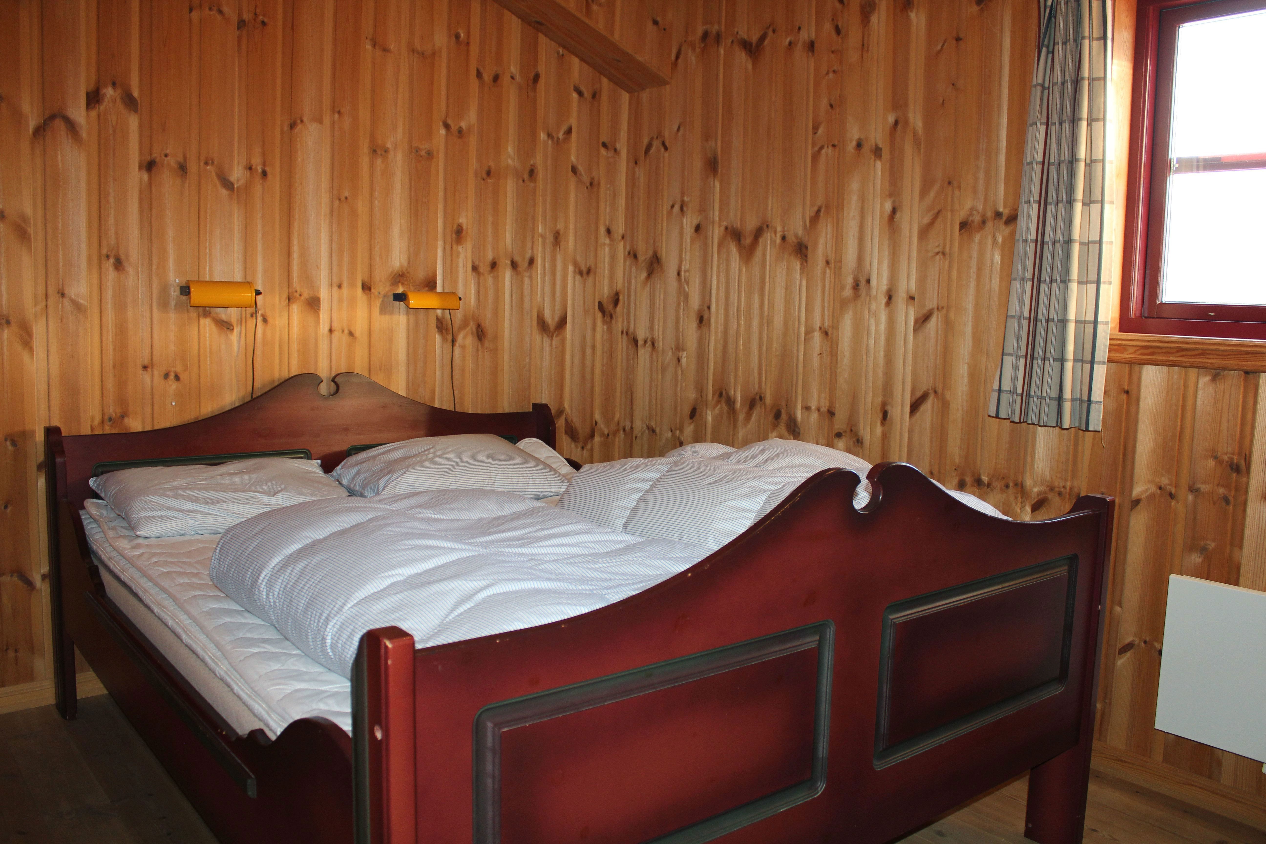 A bed with pillows and a wall with wooden panels.