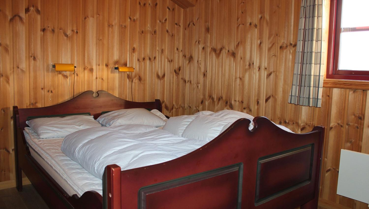 A bed with pillows and a wall with wooden panels.