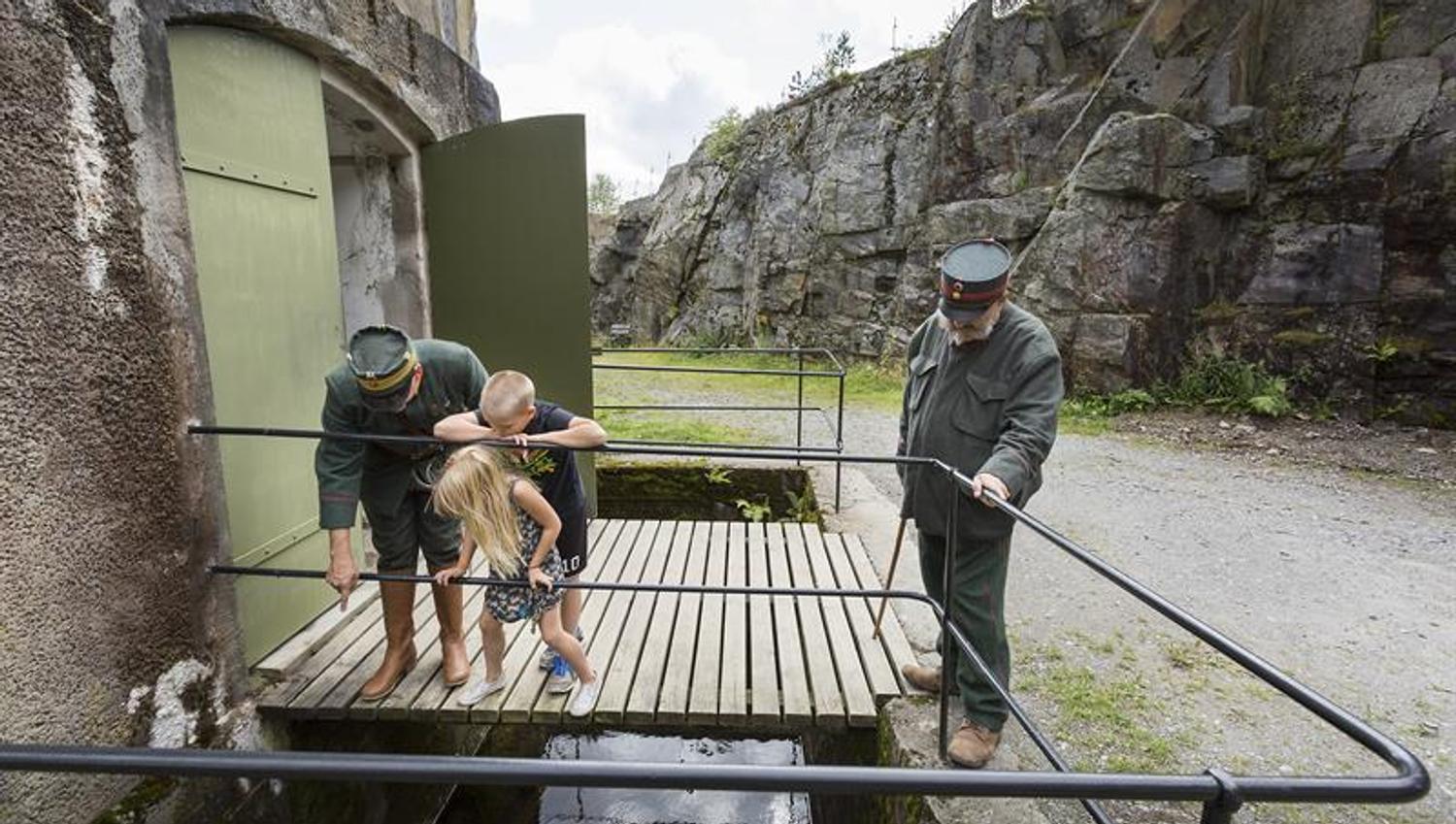 to menn i militær uniform og to barn som utforsker en festning