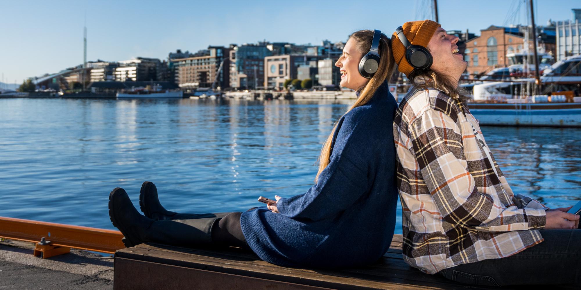 Two friends listening to podcast by the fjord in Oslo