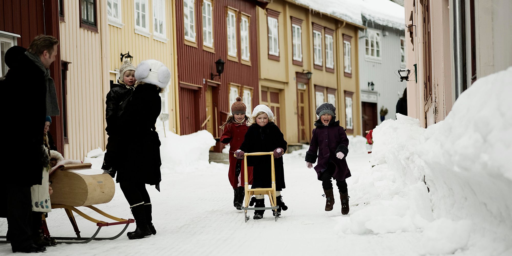 Bambine usano la slitta a spinta per andare in giro per le strade di Røros nel Trøndelag, in inverno