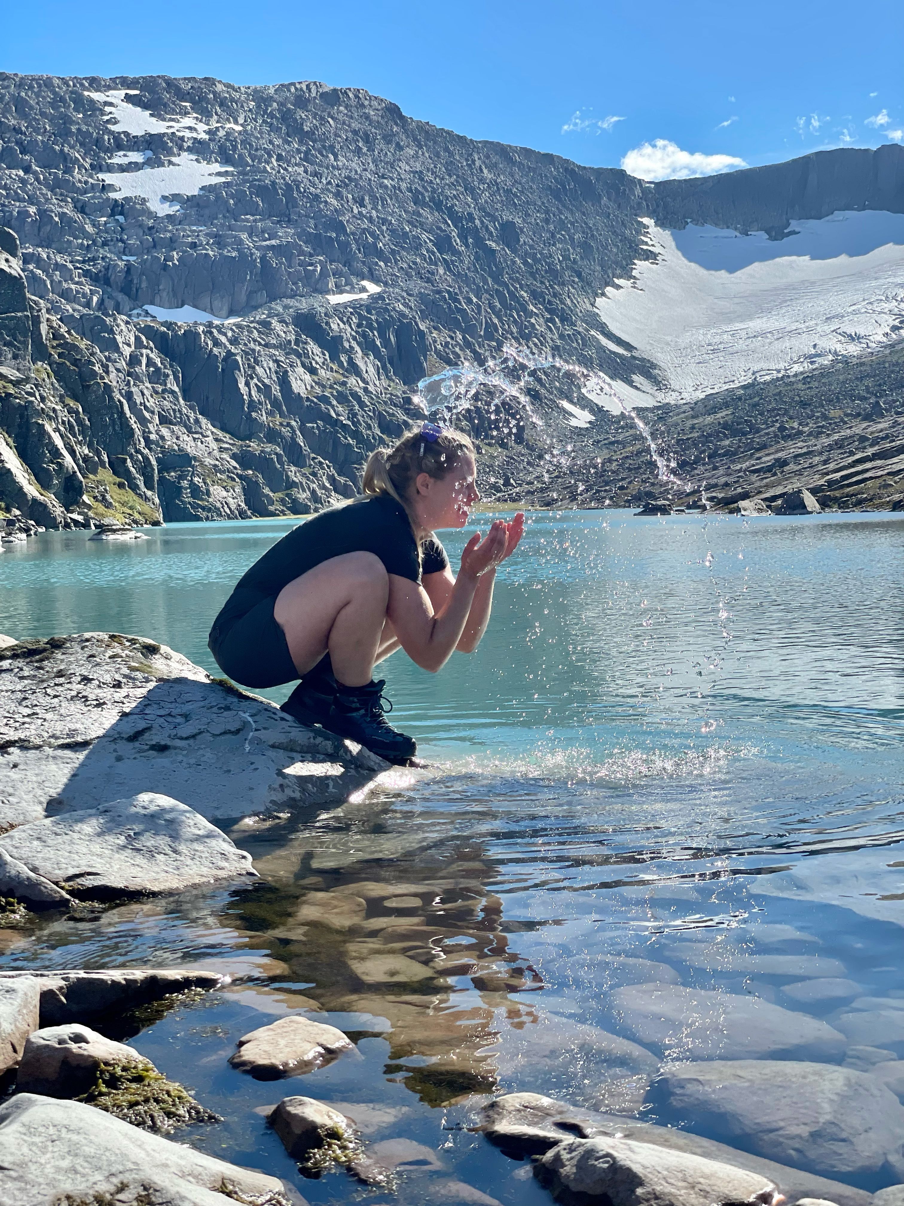 Woman splashing water in her face by hylle 7, shelf 7 in the mountains near the Ålfotbreen glacier in Fjord Norway