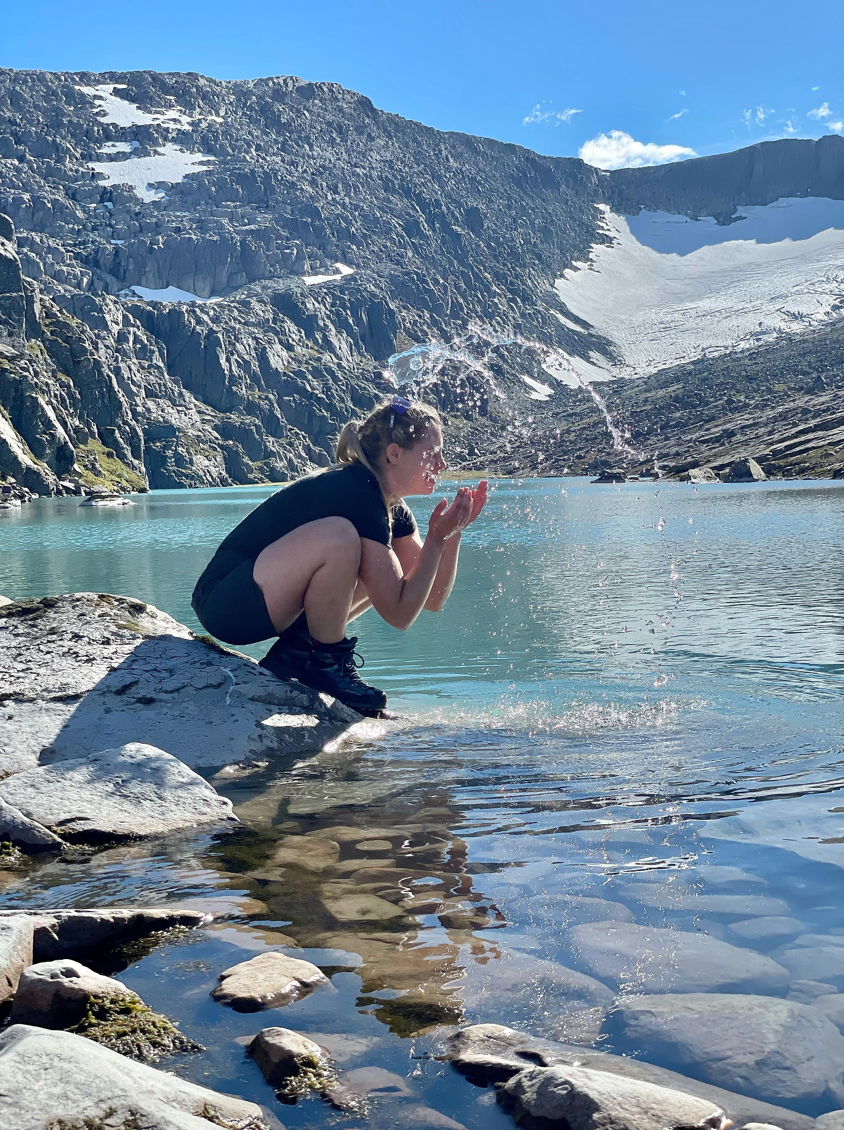 Woman splashing water in her face by hylle 7, shelf 7 in the mountains near the Ålfotbreen glacier in Fjord Norway