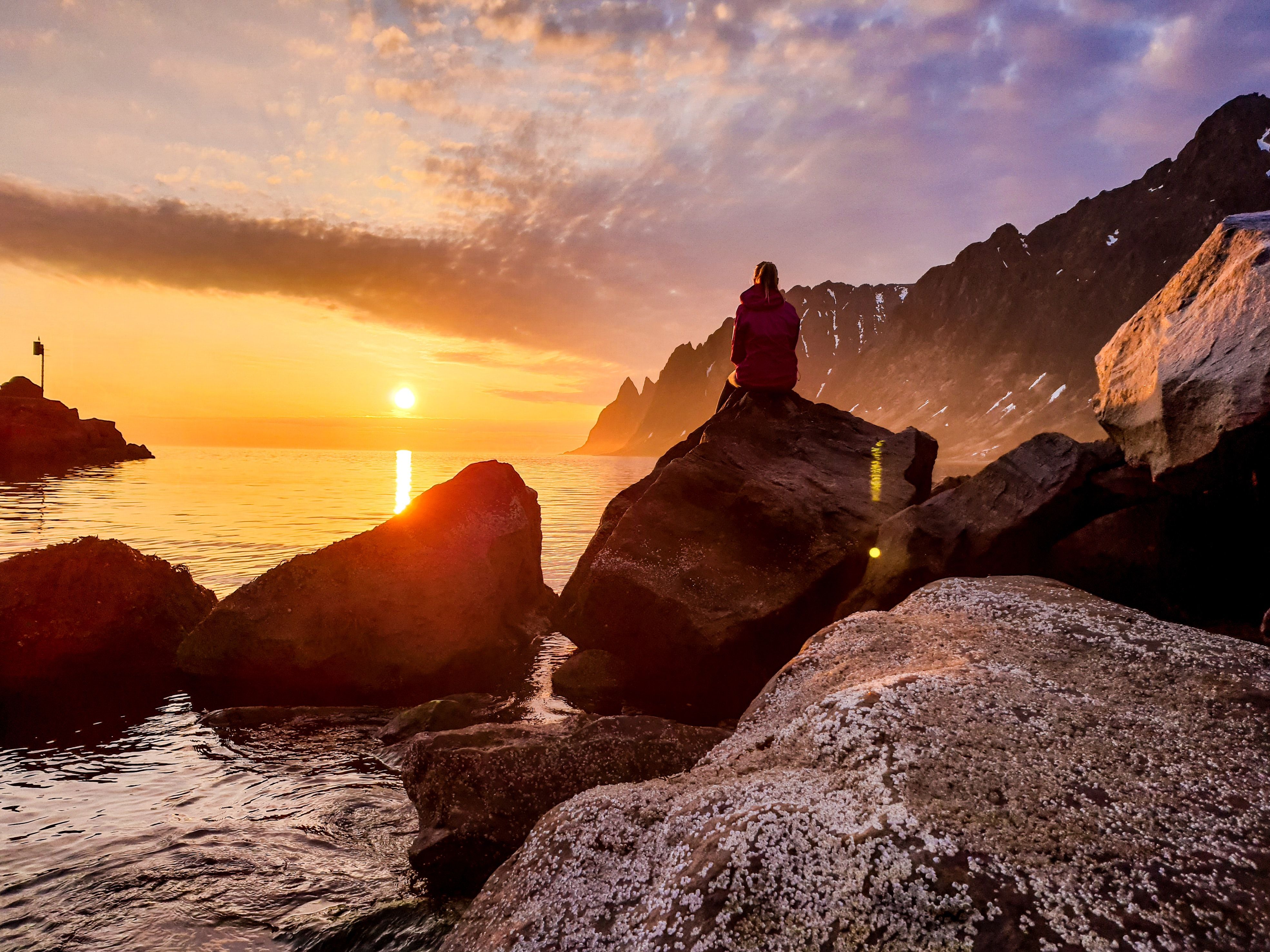 A person watching the midnight sun at Senja in Northern Norway