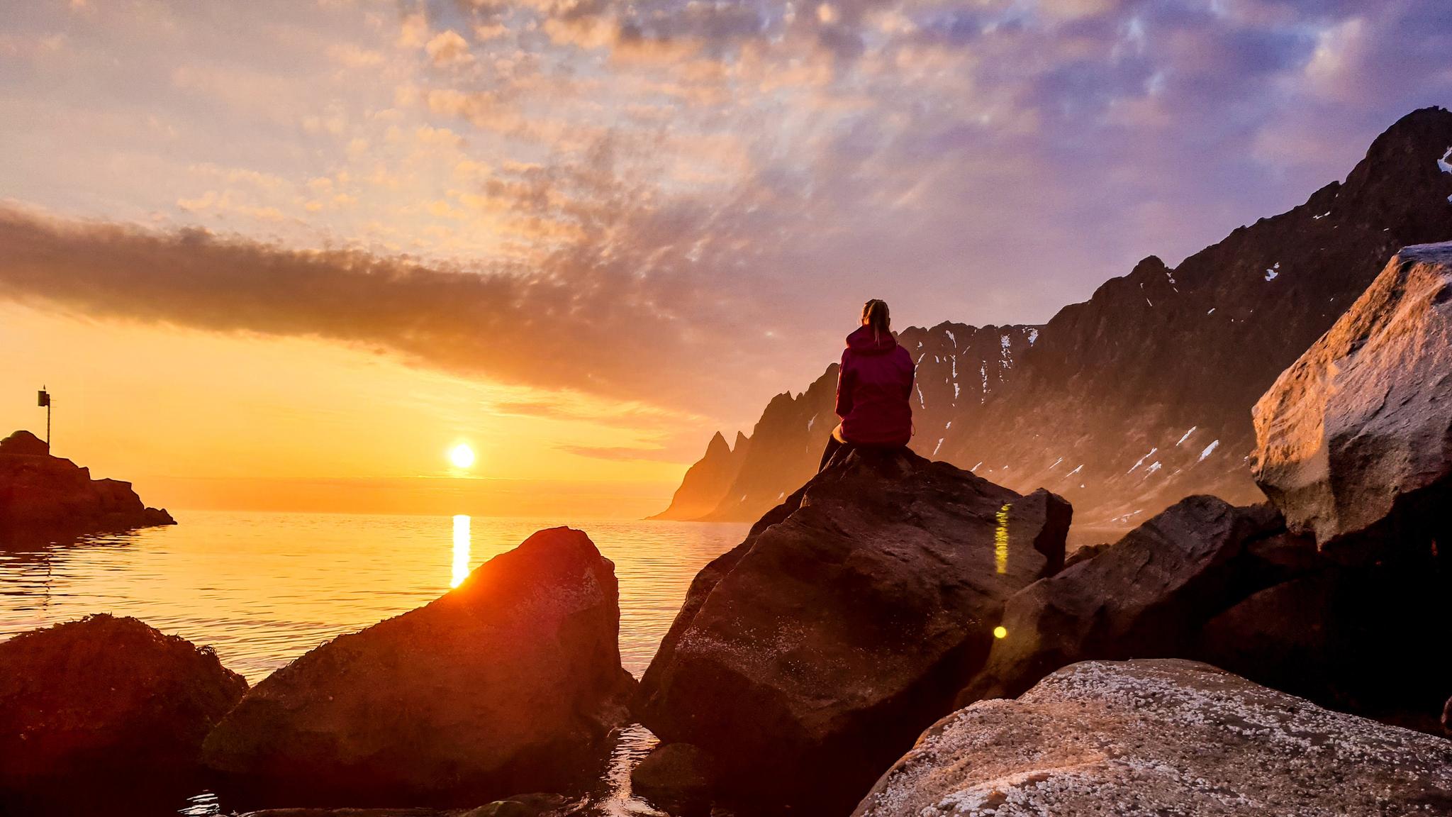 A person watching the midnight sun at Senja in Northern Norway
