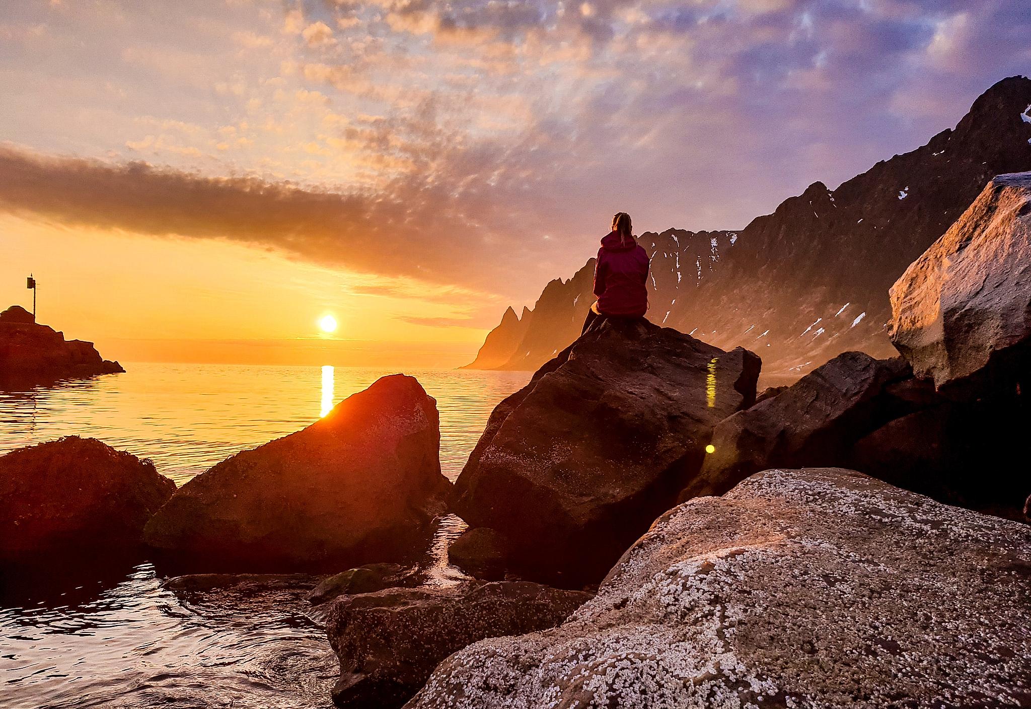 A person watching the midnight sun at Senja in Northern Norway