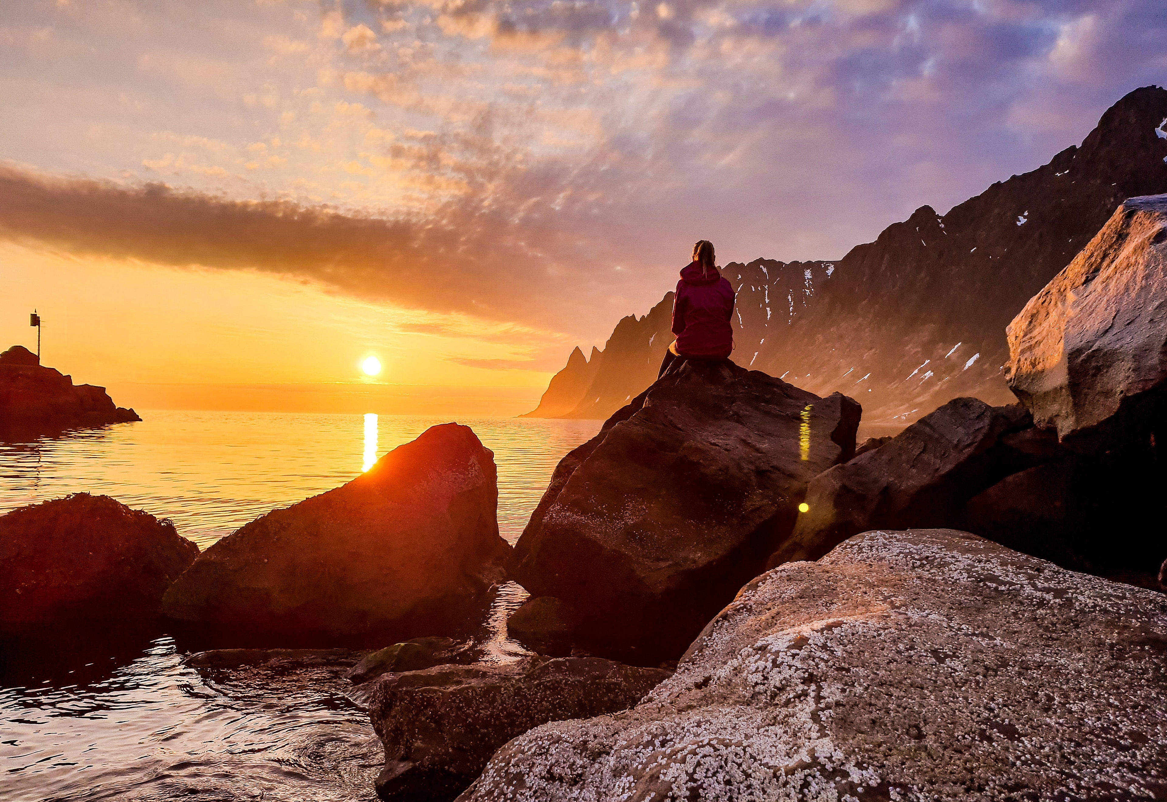 A person watching the midnight sun at Senja in Northern Norway