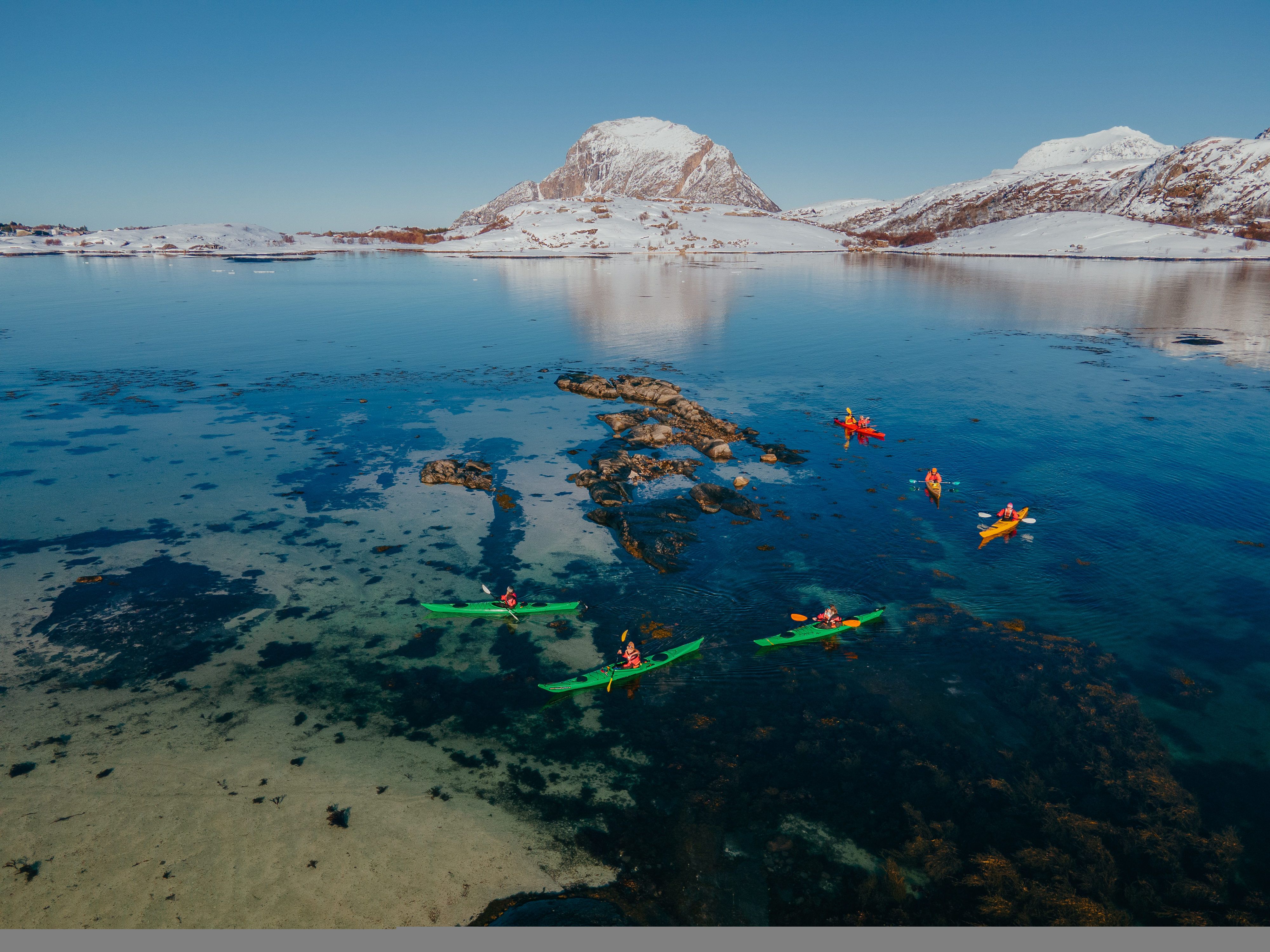 People kayaking in winter landscape.
