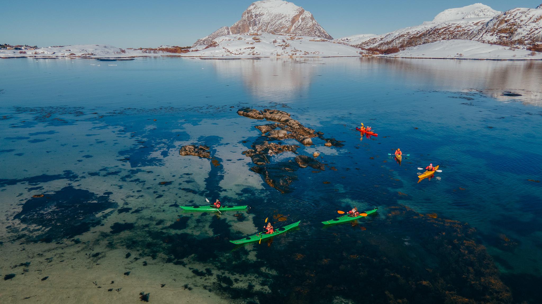 People kayaking in winter landscape.