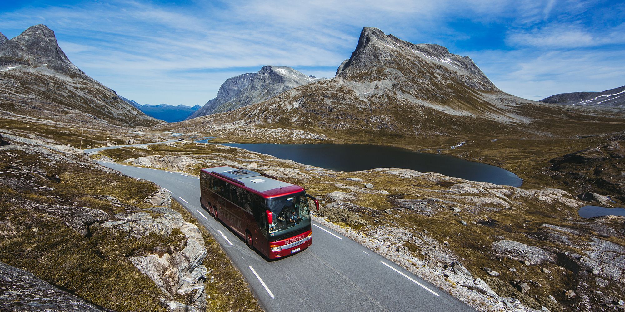 A bus driving next to a lake on a sunny day in Northwest