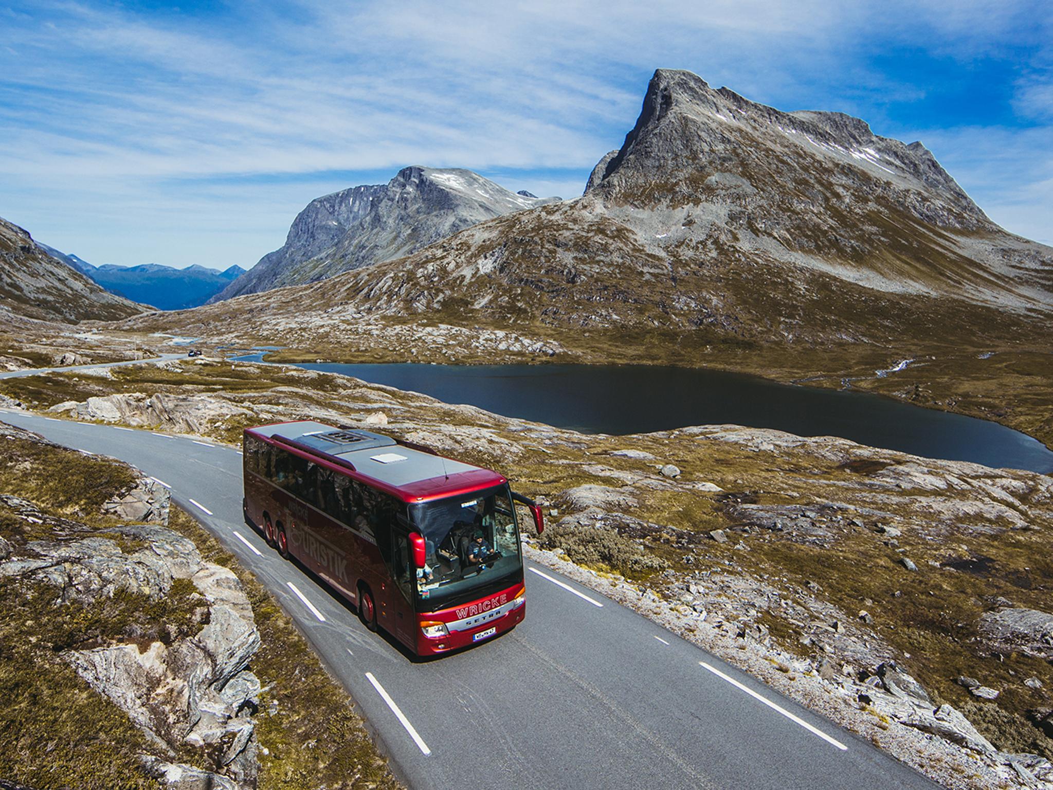 A bus driving next to a lake on a sunny day in Northwest