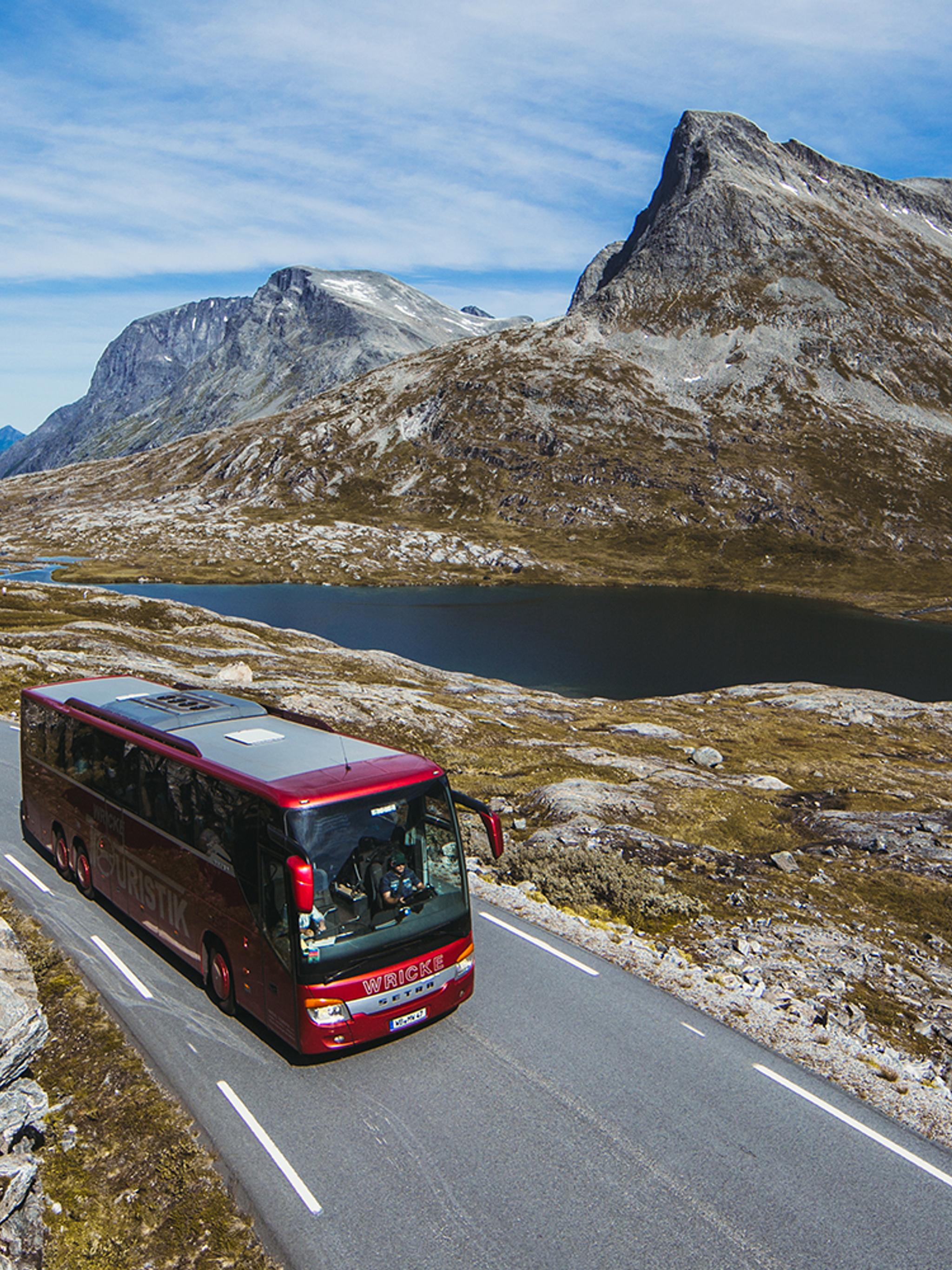 A bus driving next to a lake on a sunny day in Northwest