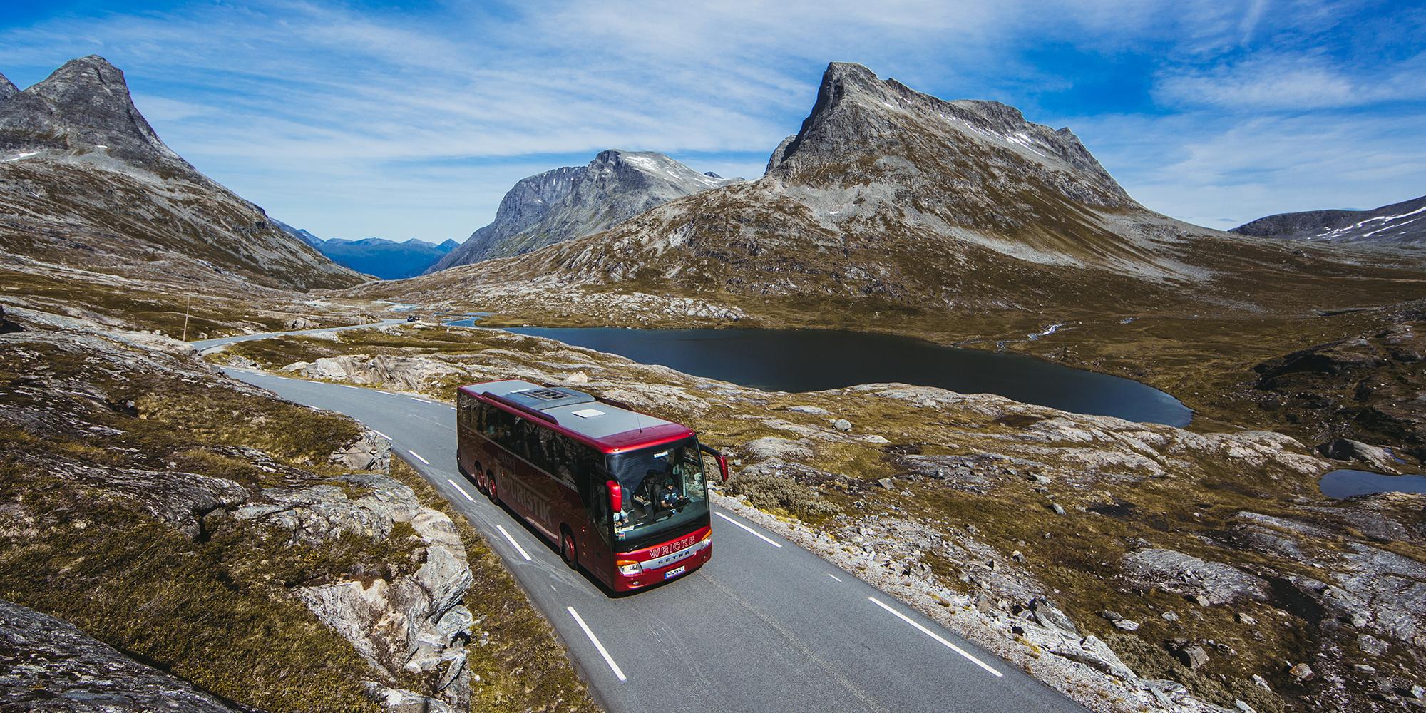 A bus driving next to a lake on a sunny day in Northwest