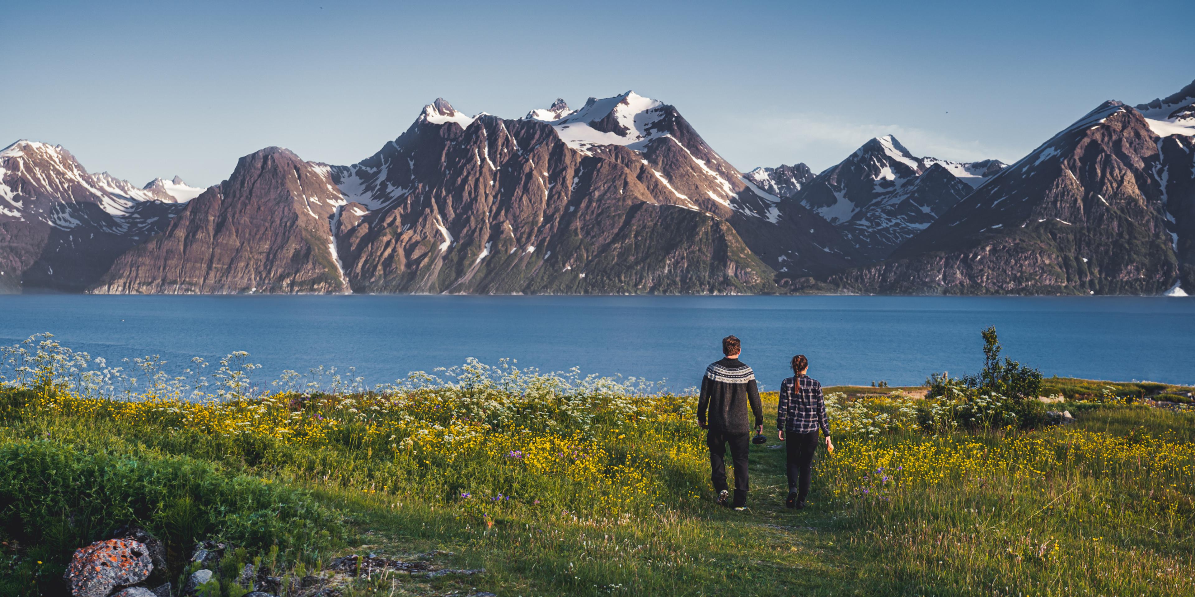 Two people walking hand in hand in the scenic mountain landscape of Lyngenfjord, Northern Norway