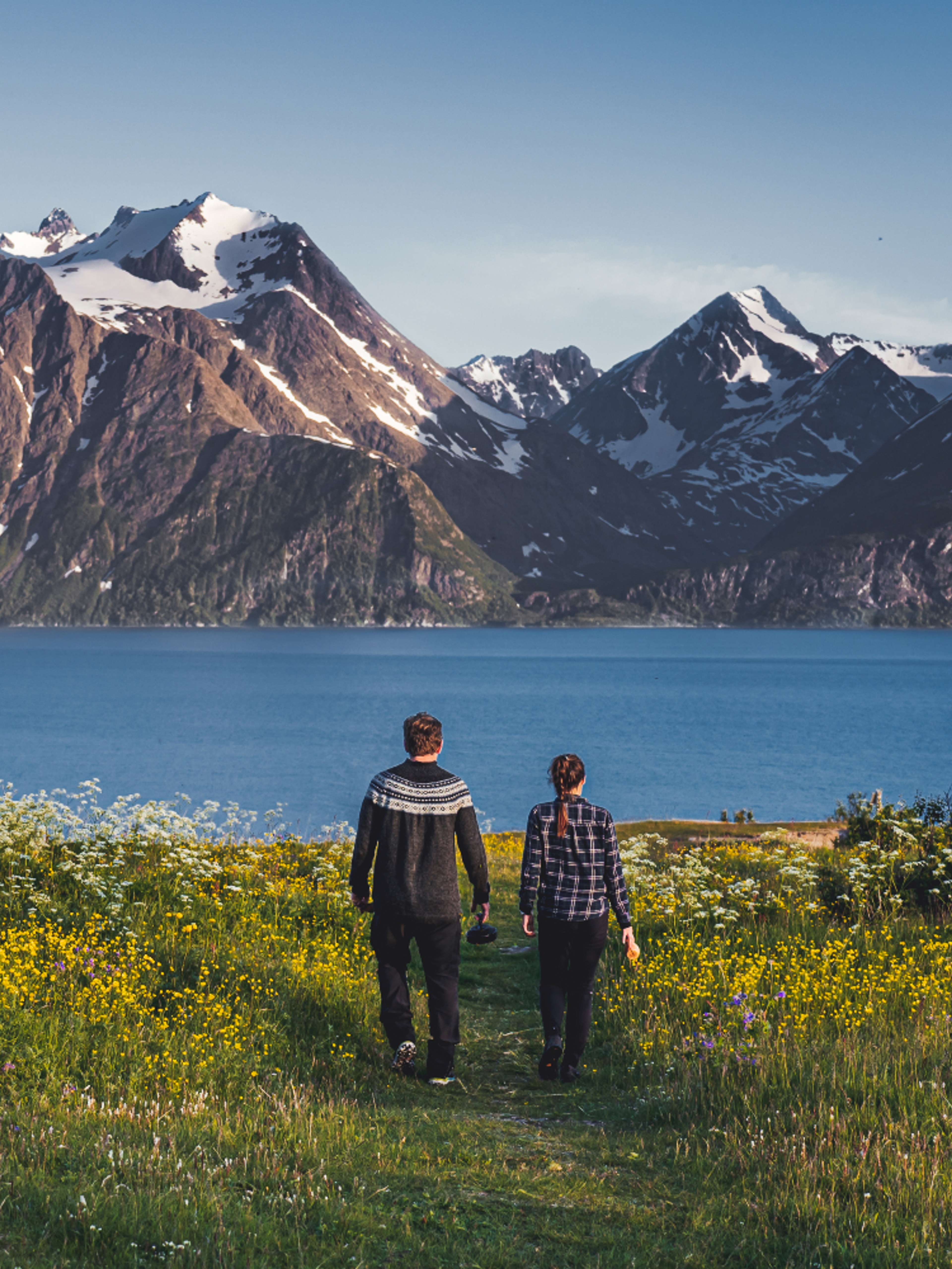 Two people walking hand in hand in the scenic mountain landscape of Lyngenfjord, Northern Norway
