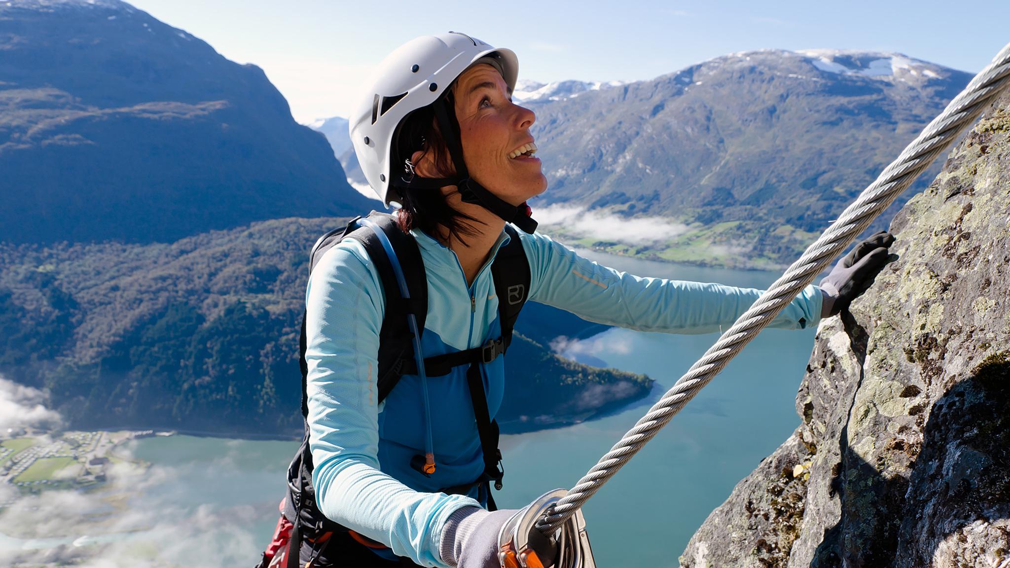 En dame klatrer en fjellvegg i Loen