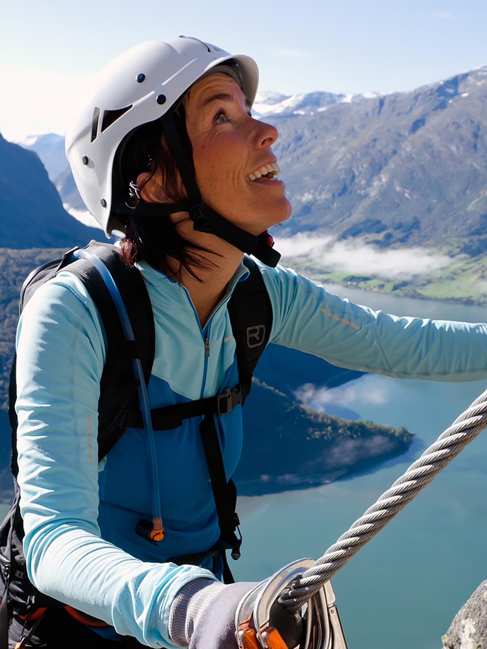 En dame klatrer en fjellvegg i Loen