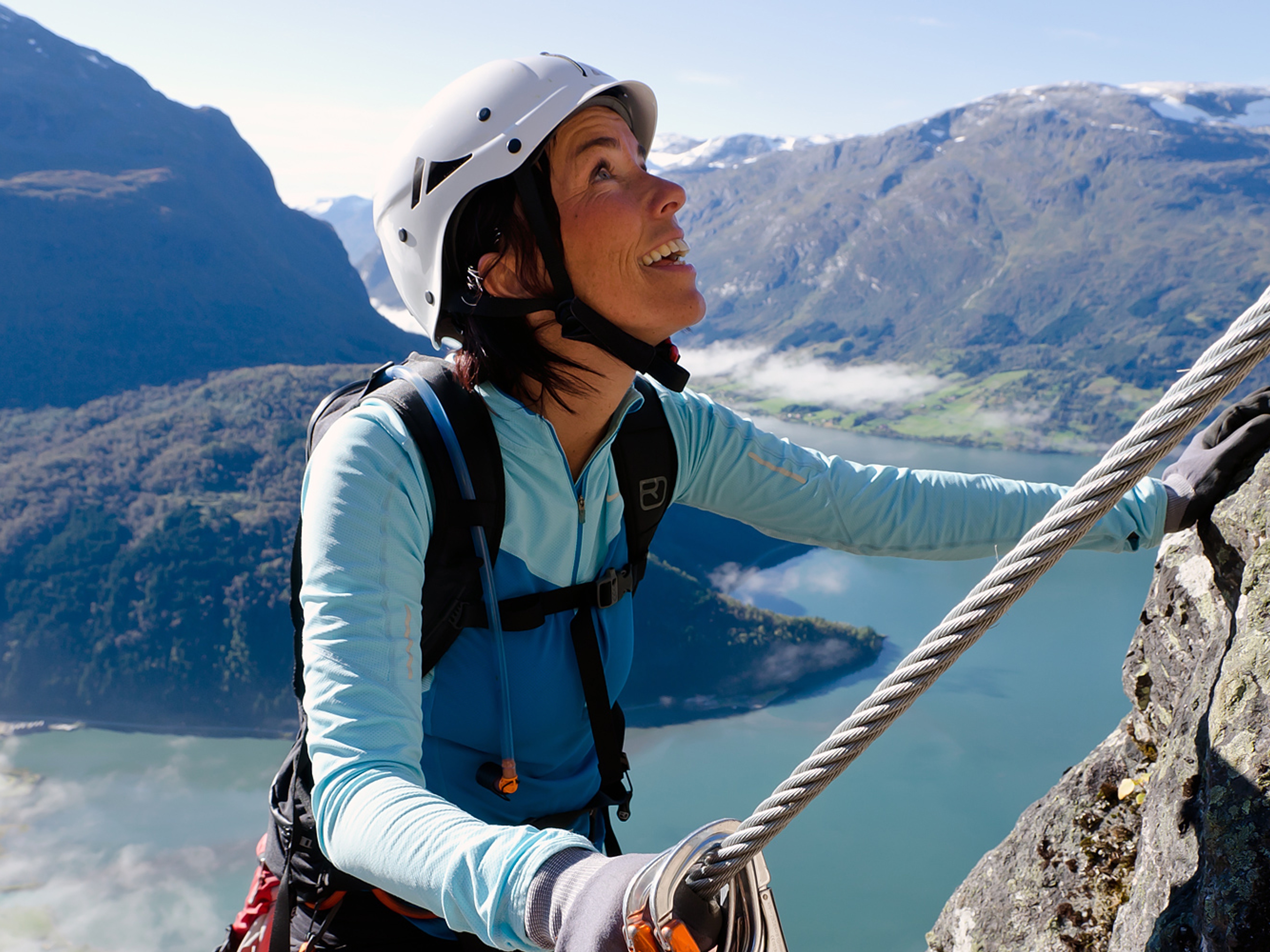 En dame klatrer en fjellvegg i Loen