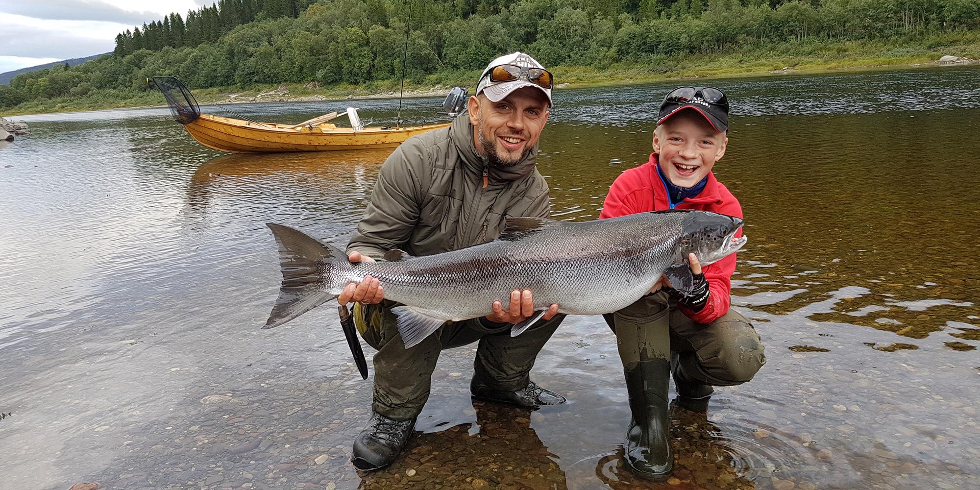 Far og sønn holder opp en stor laks de har fisket i Namsen i Namdalen i Trøndelag